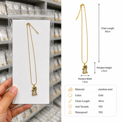 A gold-toned stainless steel pendant necklace with a small cat figure, shown hanging on a white card inside a clear plastic sleeve, held by a hand on the left, and a dimension diagram on the right showing chain length 40cm and pendant height details.