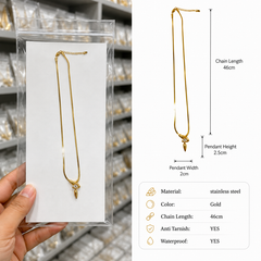 A gold stainless steel chain necklace with a decorative pendant, shown in a clear plastic display pouch held by a hand on the left, alongside a white dimension diagram on the right detailing the chain length of 46cm, pendant height of 2.5cm, and pendant width of 2cm.